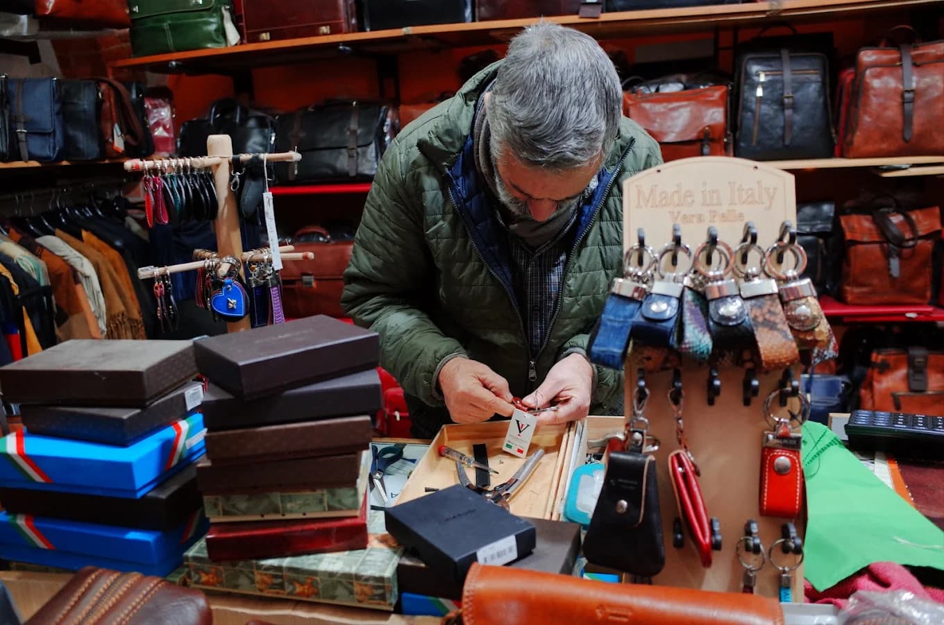 Roberto al lavoro su un accessorio in pelle, con l'insegna Made in Italy Vera Pelle
